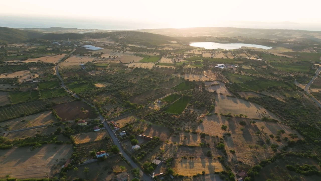 日落时的田野鸟瞰图，临湖临海的村庄田野，田野背景，晴朗的夏夜，绿色的耕地和正在生长的庄稼和遥远的村庄房屋的鸟瞰图视频素材