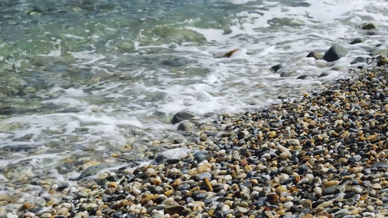 海浪在卵石上翻滚。在阳光明媚的日子在海边度假视频素材