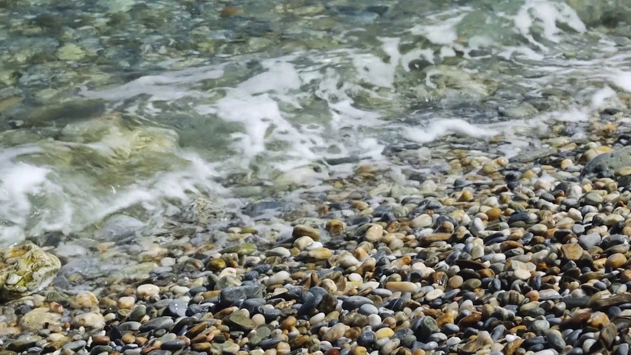 海浪在卵石上翻滚。在阳光明媚的日子在海边度假视频素材