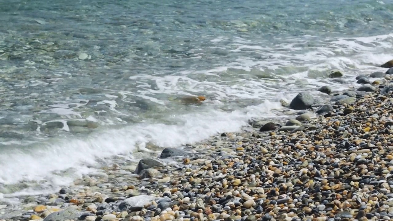 海浪在卵石上翻滚。在阳光明媚的日子在海边度假视频素材