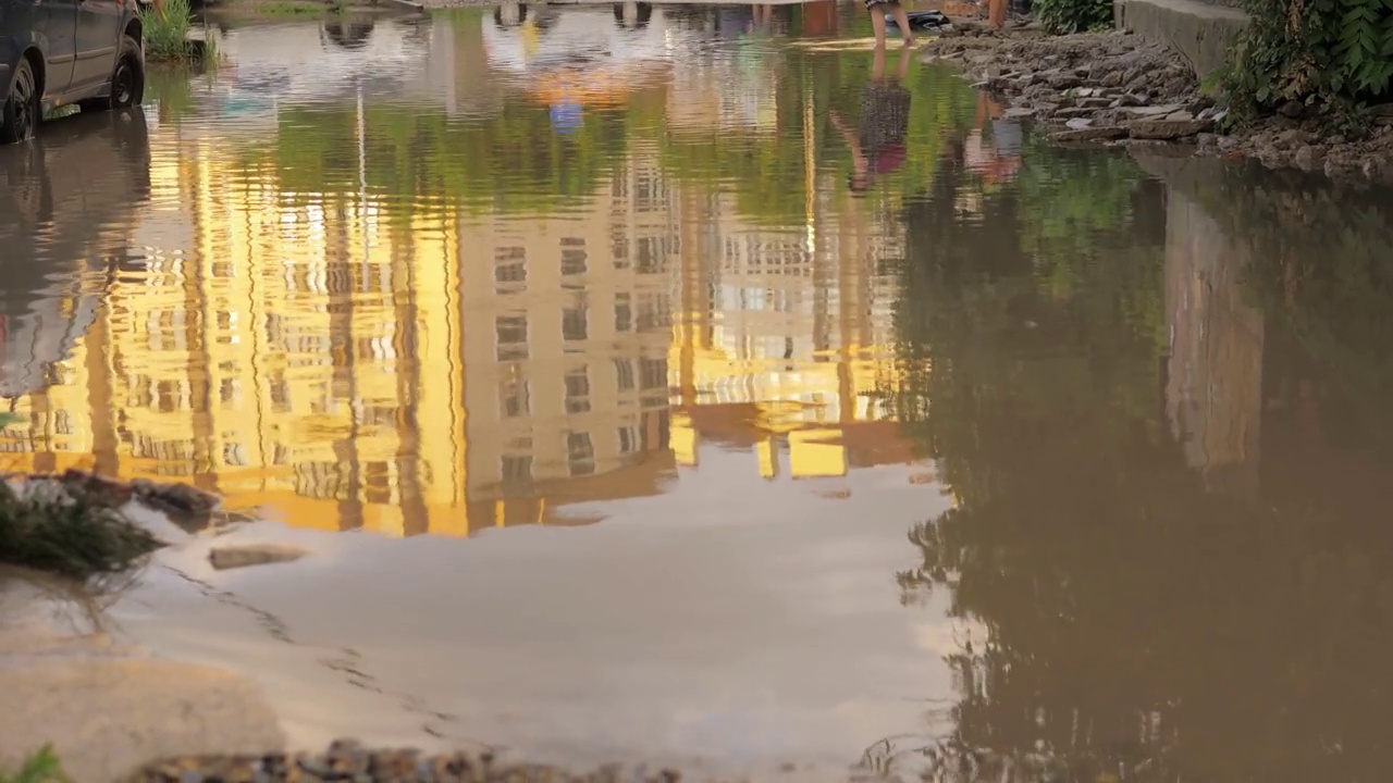 在洪水泛滥的地区驾驶汽车造成了暴雨。汽车漂浮在水面上，淹没了街道。城市道路被大水坑淹没。大雨是一种自然灾害，在道路上造成事故视频素材