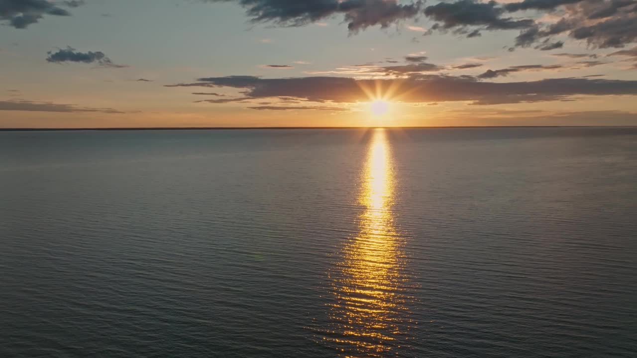 热带金色日落在海洋水的慢动作鸟瞰图。海景上的夕阳倒影。海湾无人沙滩。阳光明媚的傍晚，平静的水景。暑假。视频下载