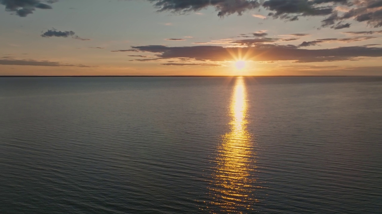 热带金色日落在海洋水的慢动作鸟瞰图。海景上的夕阳倒影。海湾无人沙滩。阳光明媚的傍晚，平静的水景。暑假。视频下载