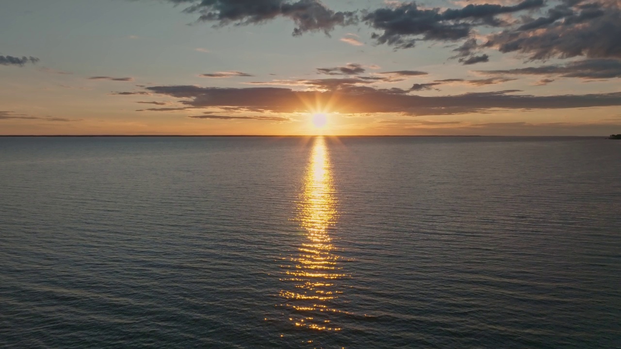 热带金色日落在海洋水的慢动作鸟瞰图。海景上的夕阳倒影。海湾无人沙滩。阳光明媚的傍晚，平静的水景。暑假。视频下载