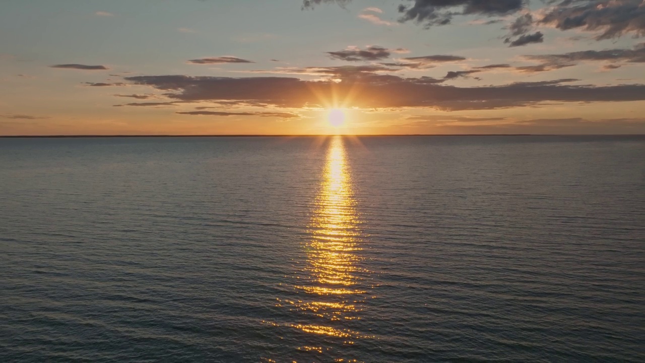 热带金色日落在海洋水的慢动作鸟瞰图。海景上的夕阳倒影。海湾无人沙滩。阳光明媚的傍晚，平静的水景。暑假。视频下载