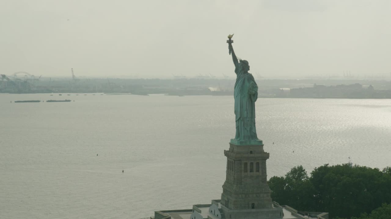 从右到左拍摄自由女神像的空中镜头。纽约港和渡轮可见。自由国家公园可见在bg视频素材