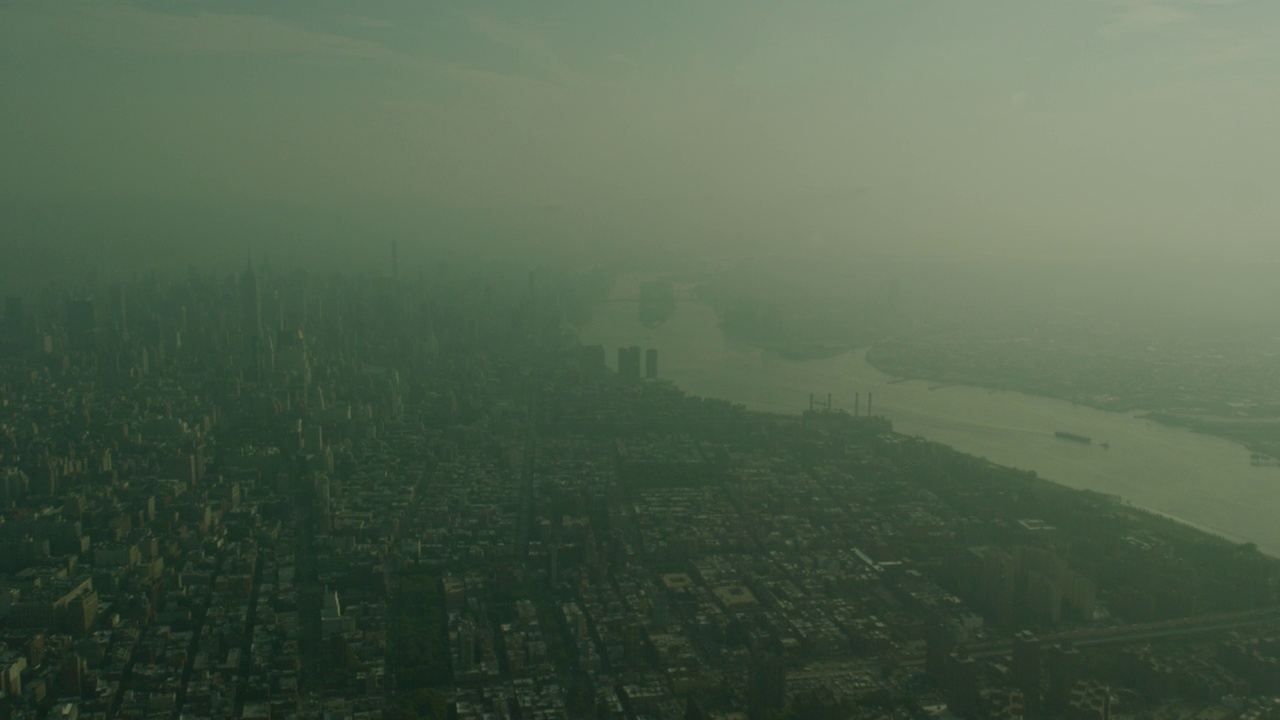 空中直线前进或沿曼哈顿北上。纽约市的天际线与高层建筑，写字楼，和摩天大楼可见。帝国大厦可见。罗斯福岛和皇后大桥在东河部分可见在bg。朦胧的天空视频素材