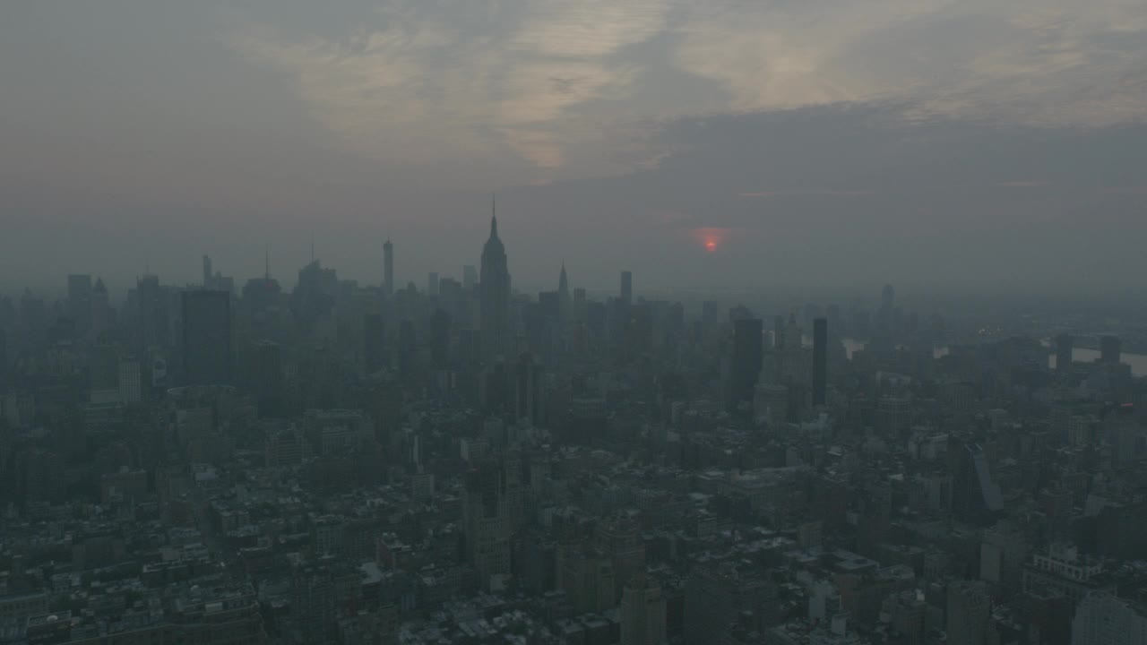 从右到左的空中移动纽约曼哈顿的天际线。帝国大厦、高楼、写字楼、摩天大楼随处可见。镜头对准哈德逊河和码头。可能是日出还是日落视频素材