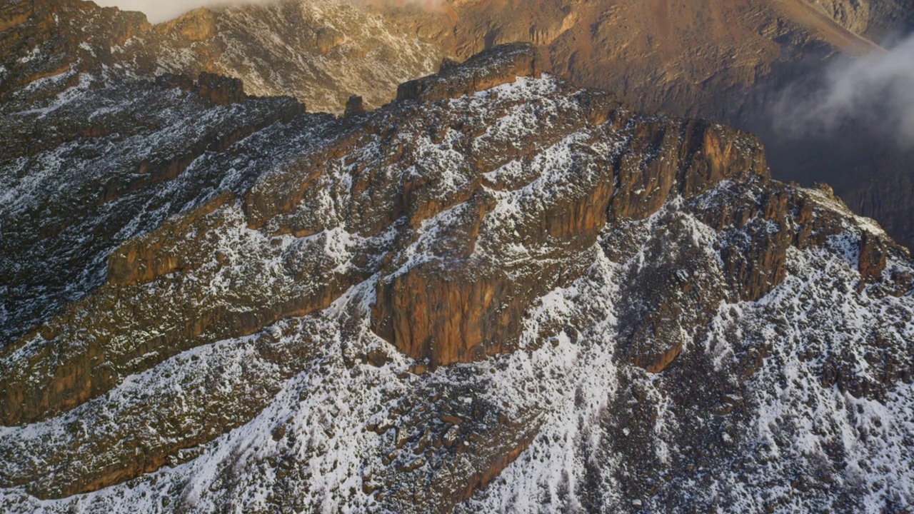 从积雪覆盖的山峰到远处肯尼亚的山峰的航拍照片。视频素材