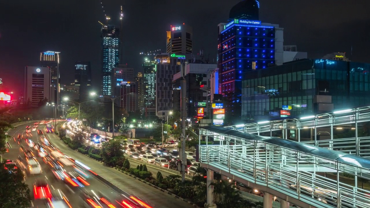 印尼首都和最大城市雅加达的现代天际线前的夜间交通延时视图，放大视频素材