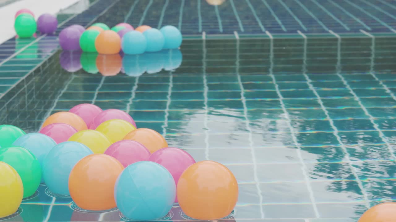 侧视图与复制空间的美丽游泳池，漂浮的彩色塑料球，展示休闲、度假、度假时光的享受和幸福的背景概念。视频素材
