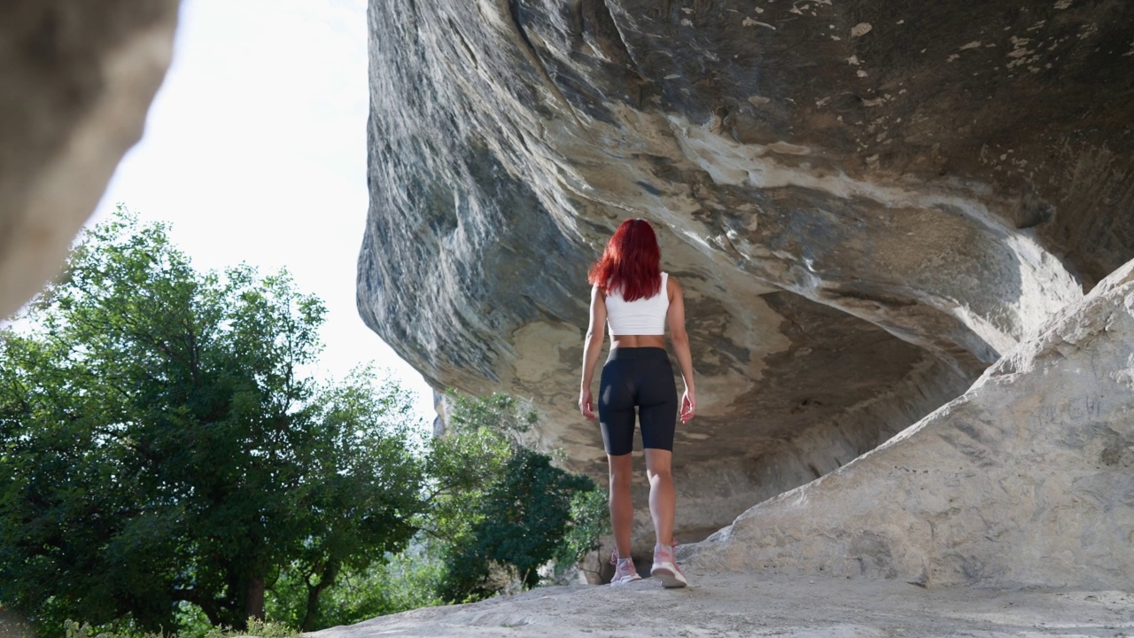 穿着运动服的苗条女人旅行者穿过洞穴走向出口视频素材