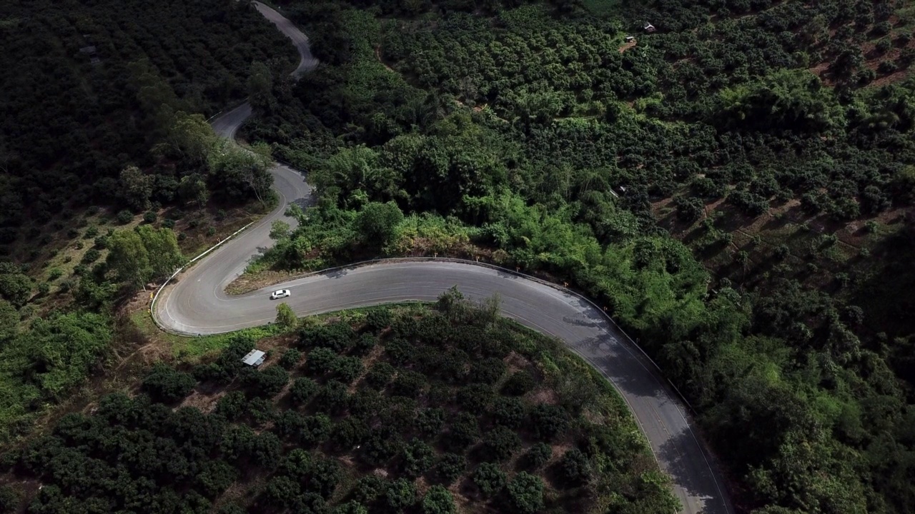 鸟瞰图汽车行驶在陡峭的道路切割通过农村领域在泰国北部地区。视频素材