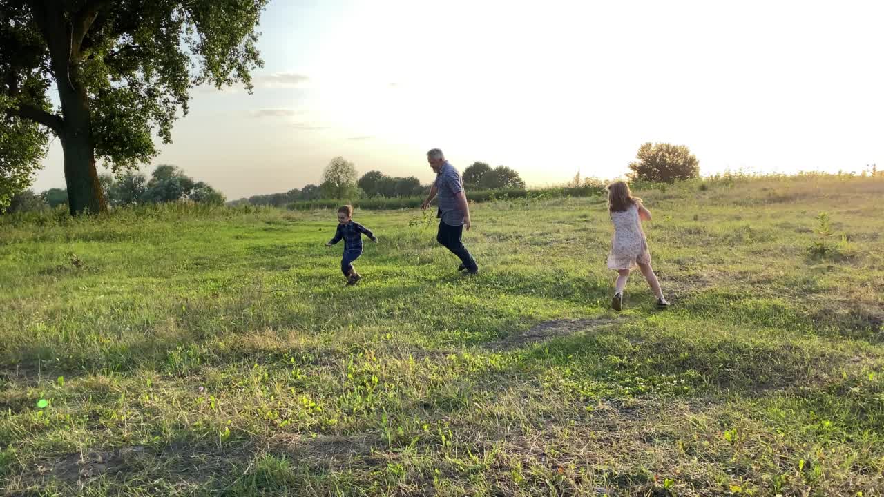 快乐的父亲和孩子们在大自然的炽热的夕阳下玩耍。视频素材