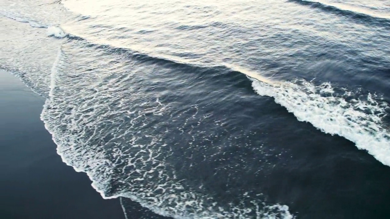 夏天海浪和黑色沙滩的鸟瞰图视频素材