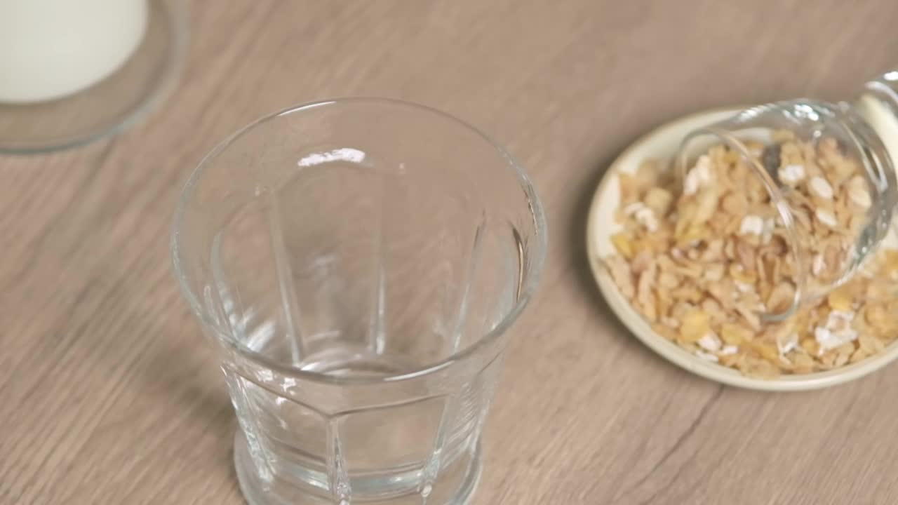 新鲜牛奶被倒入木桌上的玻璃杯中。美味的健康食品。一杯牛奶。饮食，把牛奶从玻璃瓶倒进厨房的玻璃杯里，慢动作视频素材