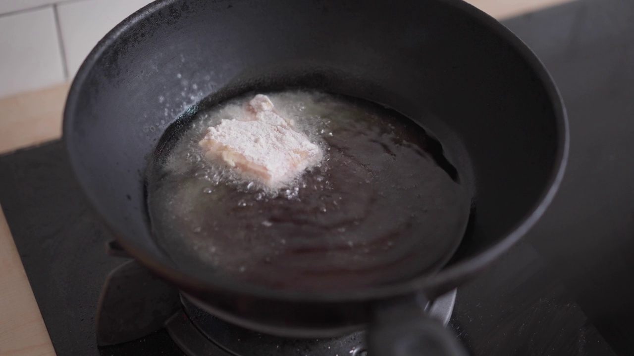 在家里厨房用油锅煎炸五花肉。不健康的亚洲食物，高胆固醇的肉类晚餐准备视频素材