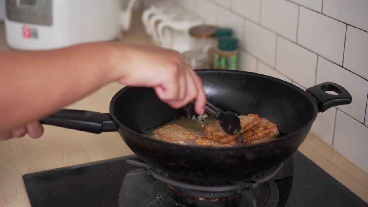 在家里厨房用油锅煎炸五花肉。不健康的亚洲食物，高胆固醇的肉类晚餐准备视频素材