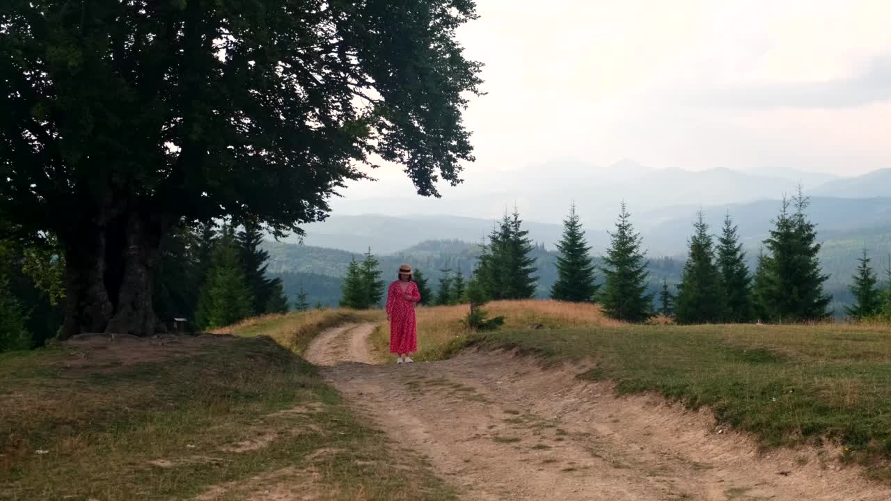 快乐的女人在红裙走在山间小道视频素材