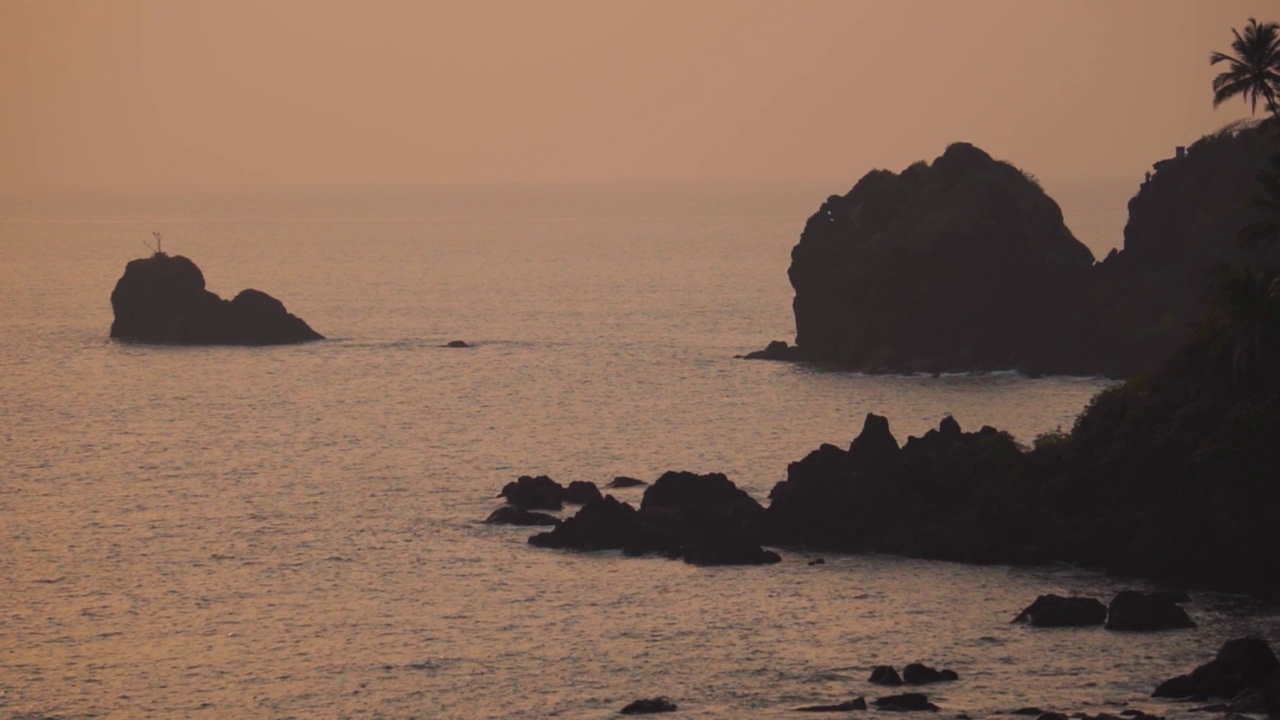 从印度果阿的Cabo De Rama看到的日落时阿拉伯海的广角照片，海水之间有岩石。自然的海洋日落背景。海水中的岩石结构视频素材