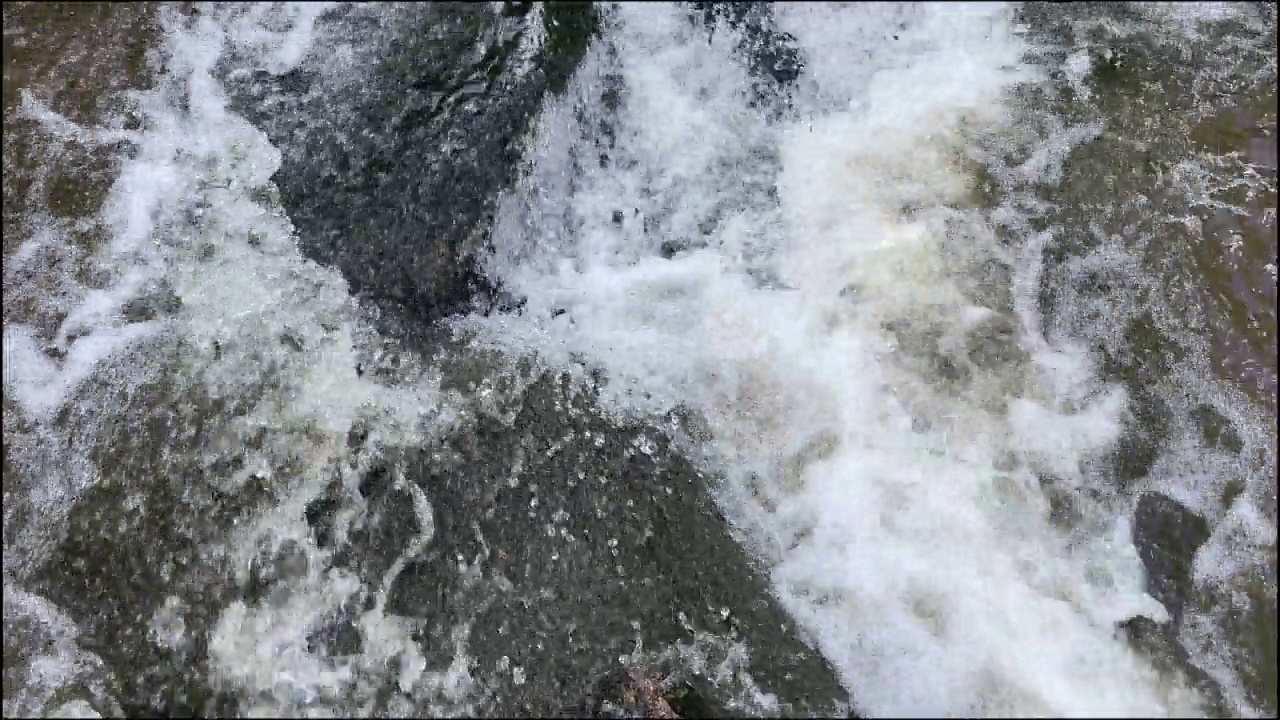 水流以泡沫撞击岩石。河水流入岩石。视频素材