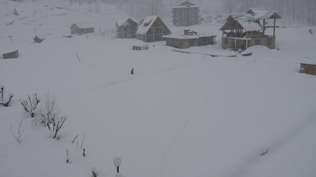 一个人独自走在白雪覆盖的小路上，在冬天的雪山谷视频素材