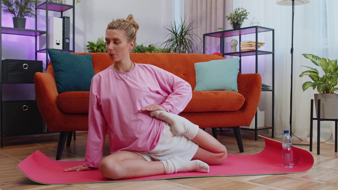 年轻女子在垫子上做瑜伽拉伸运动，锻炼，燃烧脂肪卡路里，在家训练视频素材