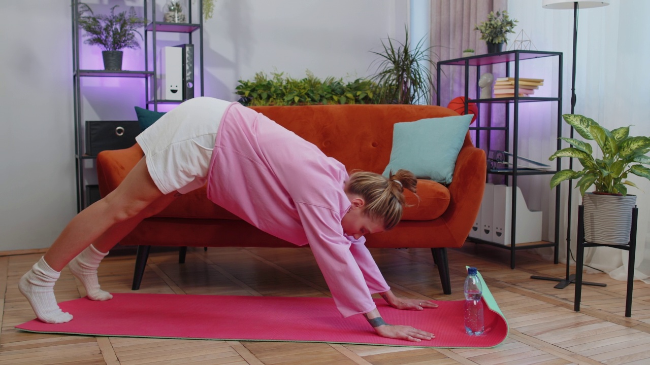 年轻女子在垫子上做瑜伽拉伸运动，锻炼，燃烧脂肪卡路里，在家训练视频素材