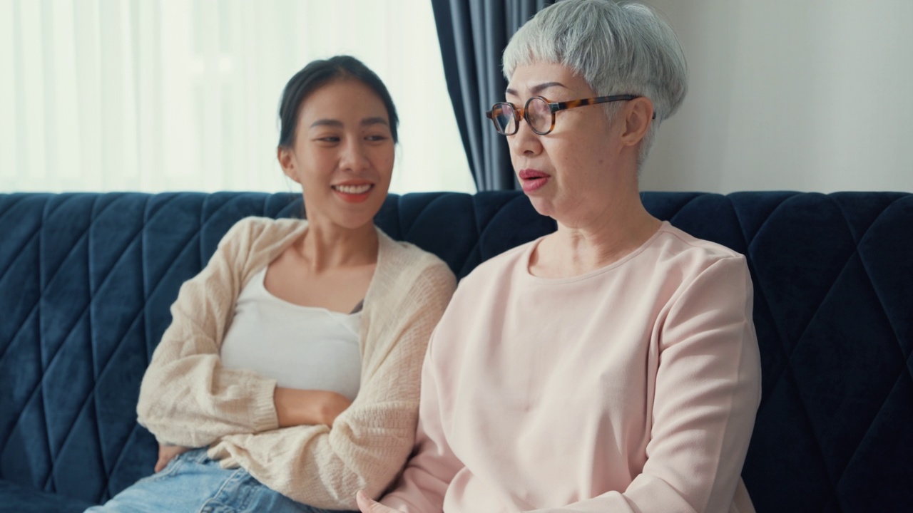 幸福的亚洲家庭，年幼的女儿和年长的妈妈分享女人的谈话，深入倾听，互相关注，一起花时间在家里的客厅。视频素材