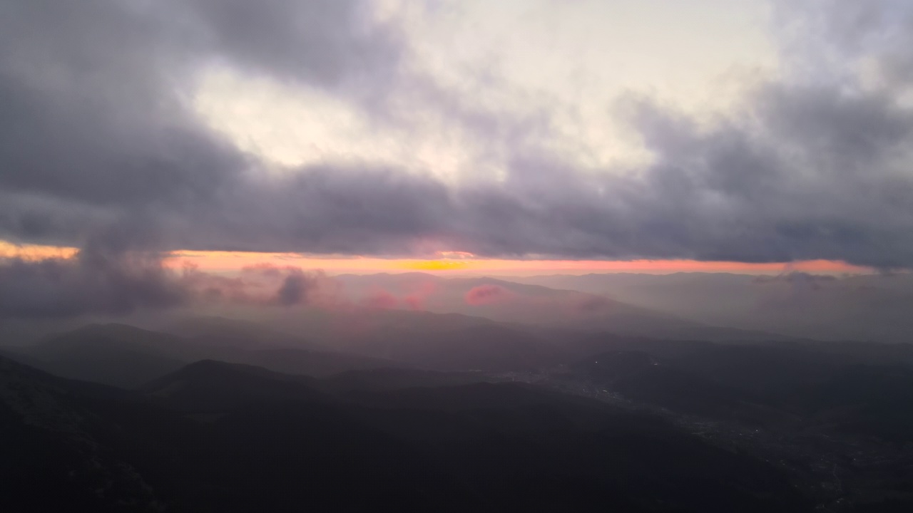 秋天日出时，明亮的雾晨在与山林树木的黑暗山峰上的鸟瞰图。清晨野生林地的美景视频素材