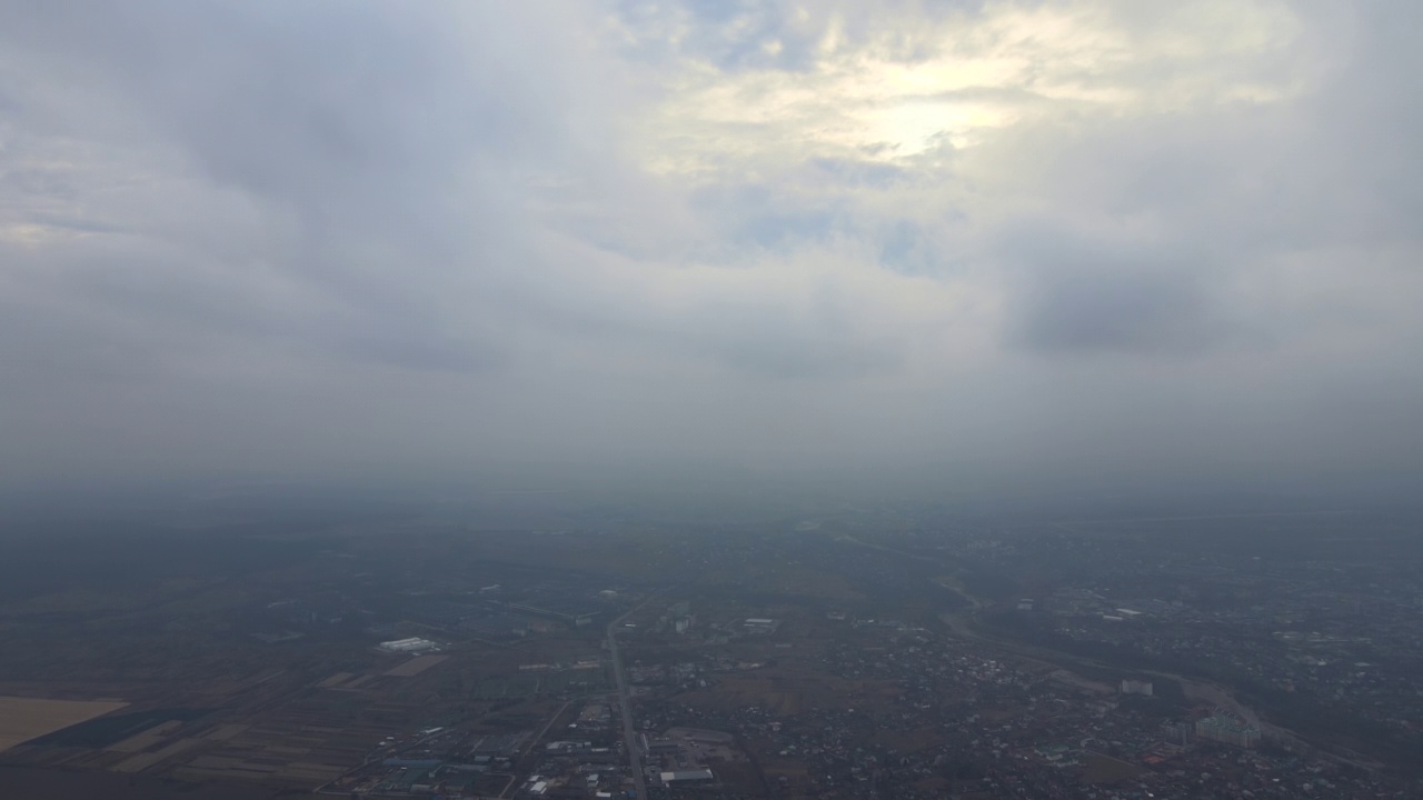 高空鸟瞰图，远处的城市被暴雨前形成的蓬松积云所覆盖。飞机视角的多云景观视频素材