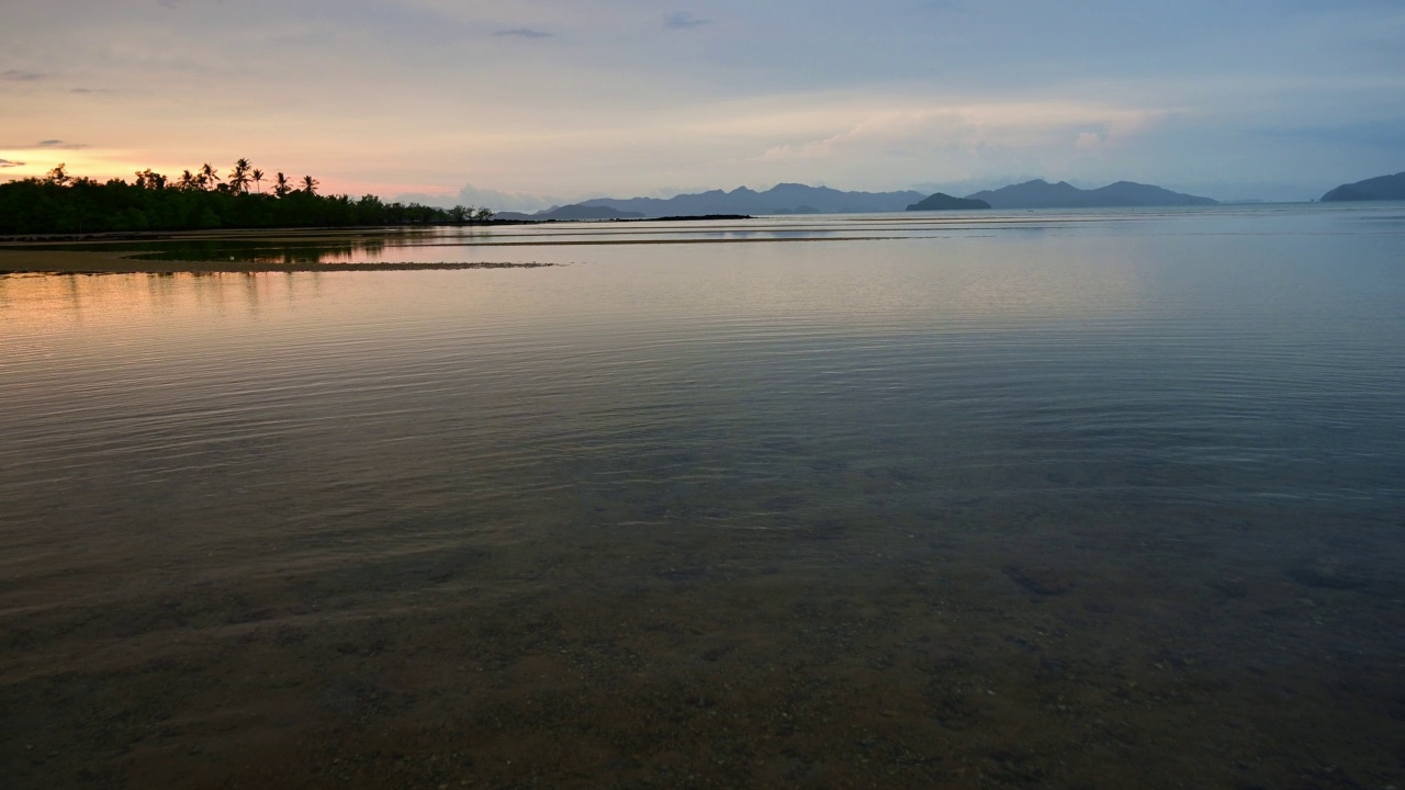 彩色的日落景色在海岛海滩与海浪和反射天空。视频素材