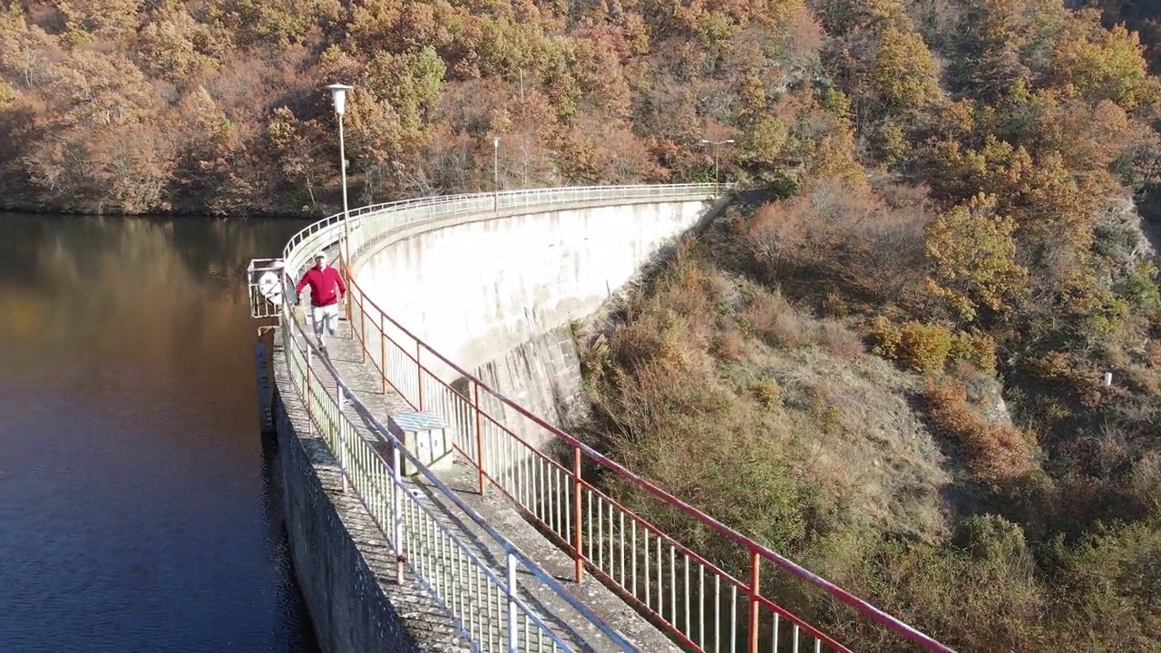 大坝桥的鸟瞰图，湖面反射出背景中五彩缤纷的秋天森林视频素材