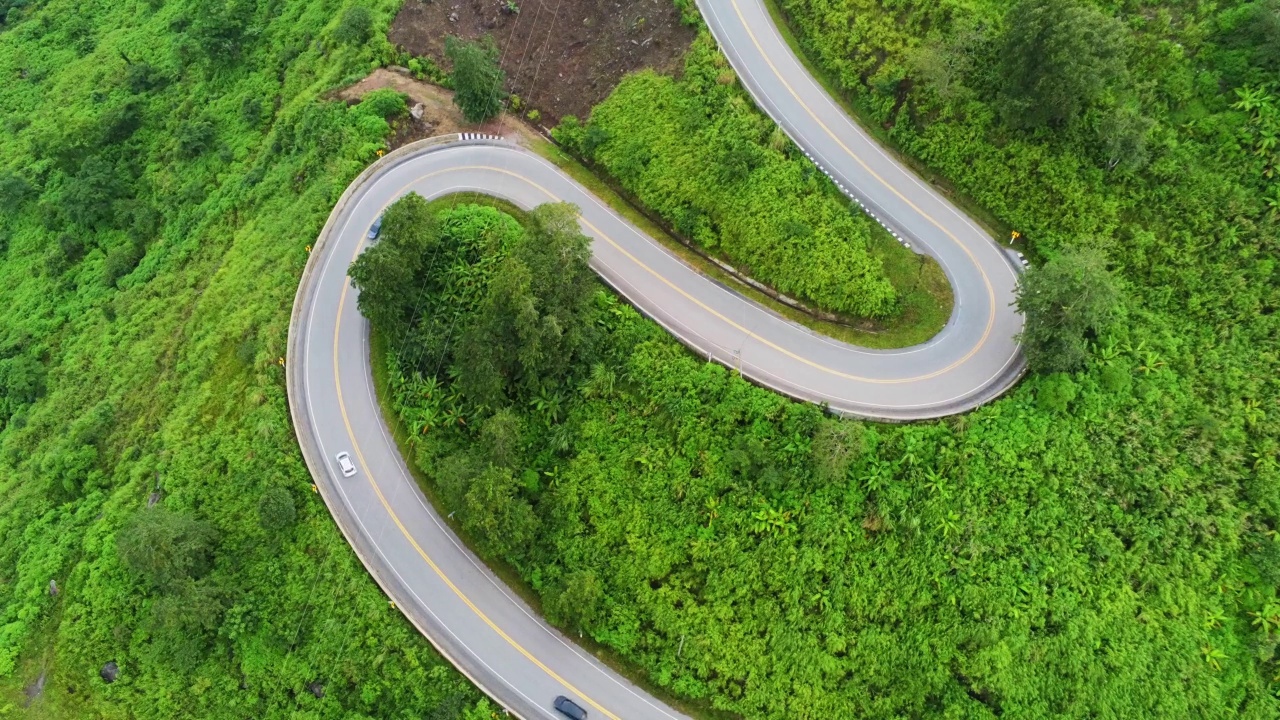 空中视频俯视图无人机道路照片在绿色山脉与白色雾漂浮和路径令人兴奋的陡峭道路的旅行方式。视频素材