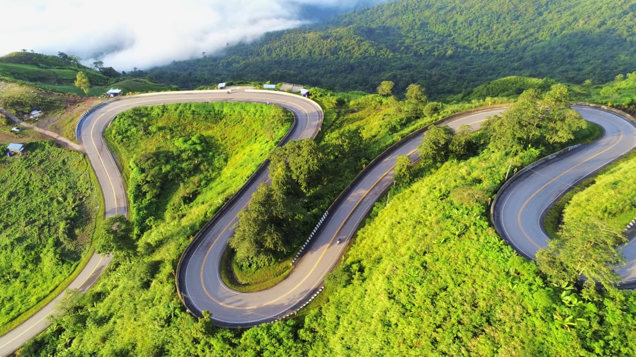 空中视频俯视图无人机道路照片在绿色山脉与白色雾漂浮和路径令人兴奋的陡峭道路的旅行方式。视频素材