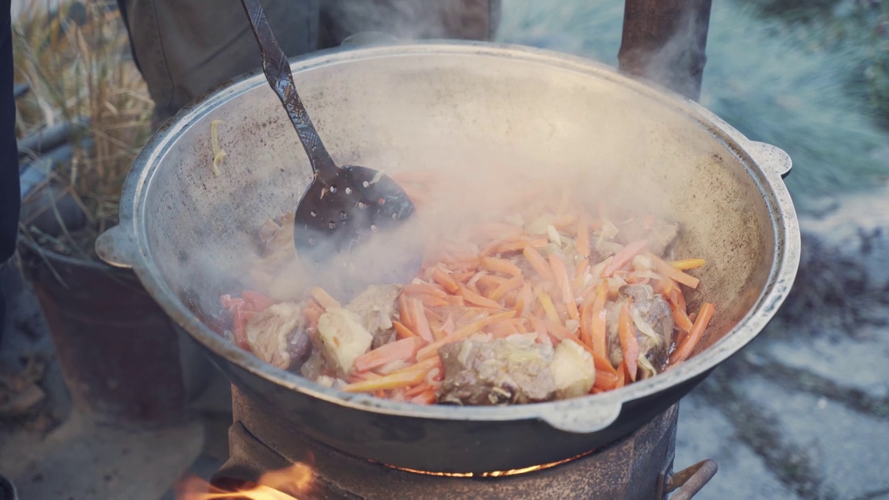 男人用漏勺把肉、蔬菜和油混合在一起。视频素材