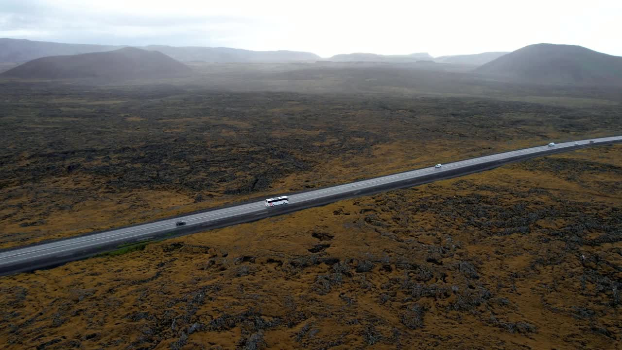 无人机镜头在冰岛熔岩地貌平原的直线道路上飞行。视频素材