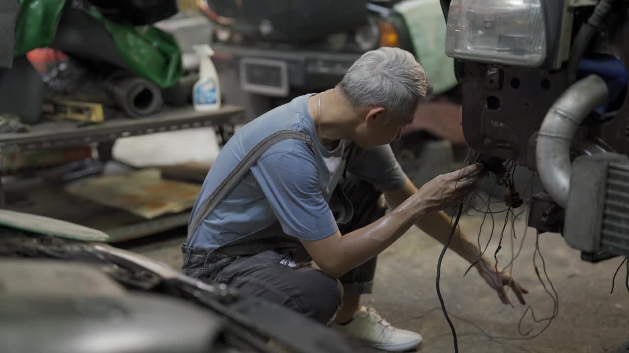 在车库工作的男性维修工程师。一个成年人经营着一家汽车修理店。视频素材