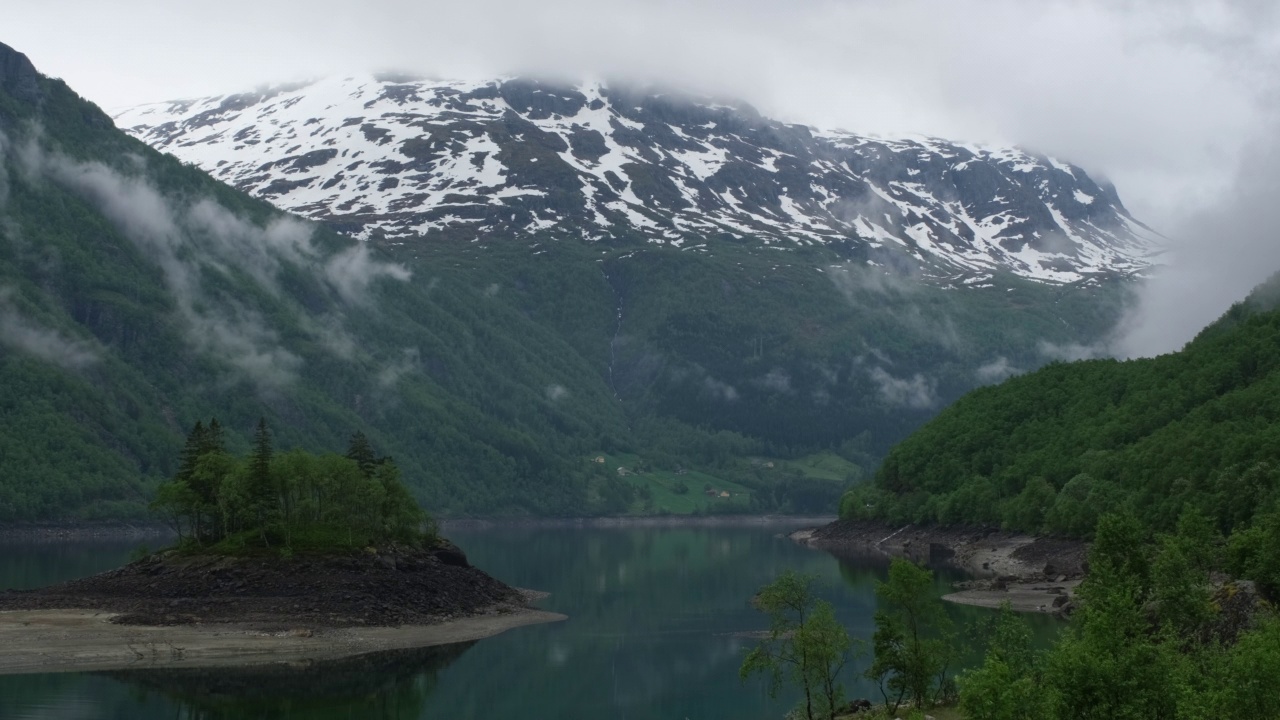 挪威美丽的风景。Vestland。Roldalsvatnet湖上一个岛屿的美丽风景。以雪为背景的山脉。阴雨绵绵的春日。4K超高清59,94fps ProRes 422 HQ 10位视频下载