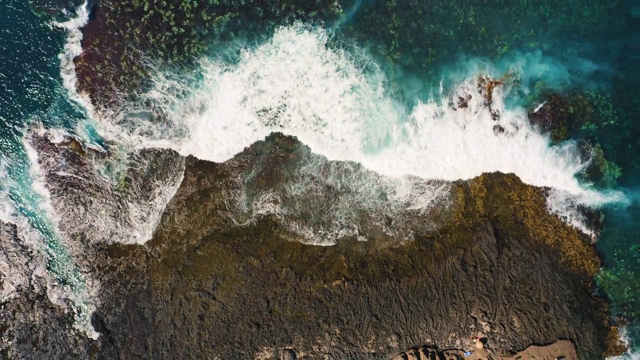 海浪在空旷的多岩石的热带海滩上拍打着泡沫，海滩上有巨大的火山构造和石头。狂野的海滩遇见深蓝色的碧水。冲浪地点。蓬胡安妮塔。西班牙加那利群岛的特内里费岛。视频素材