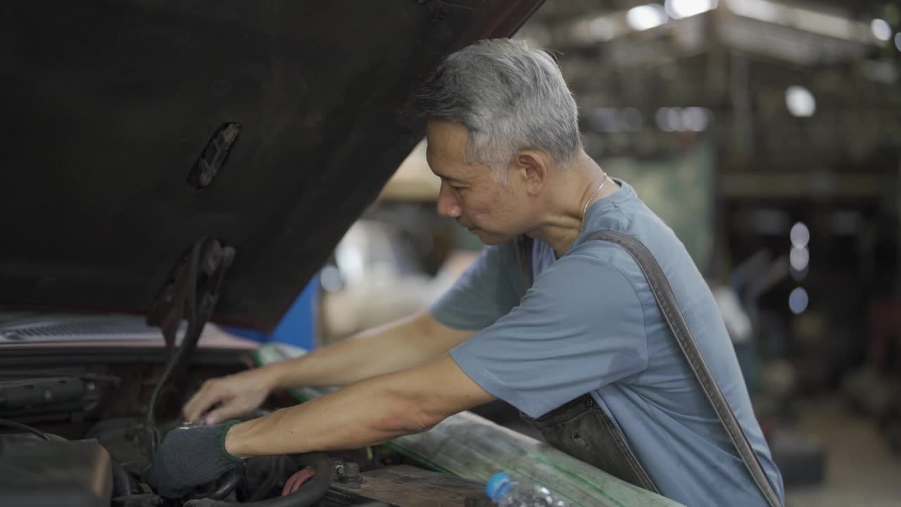 在车库工作的男性维修工程师。一个成年人经营着一家汽车修理店。视频素材