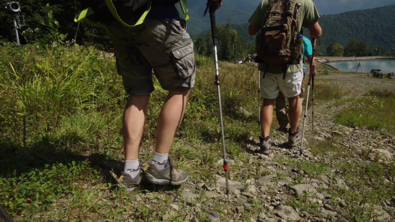 从山上下到美丽的蓝色湖泊。在高加索山区艰苦的徒步旅行后休息和放松。特殊的运动鞋使在岩石上行走更容易。光走视频素材