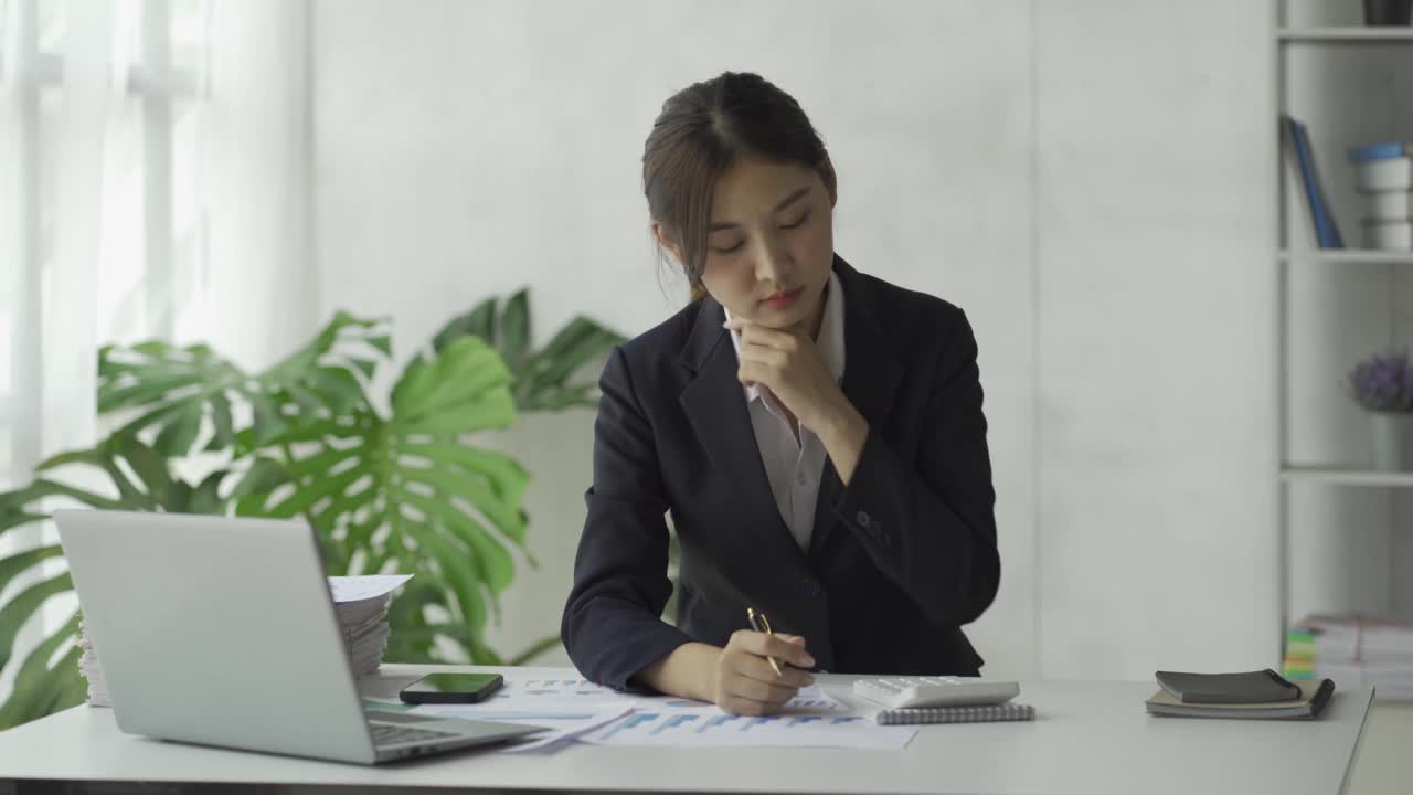 特写亚洲女商人使用计算器与税务计算器图表和图表报告的家庭收入和费用预算策划人。用笔记本电脑进行在线会议视频素材