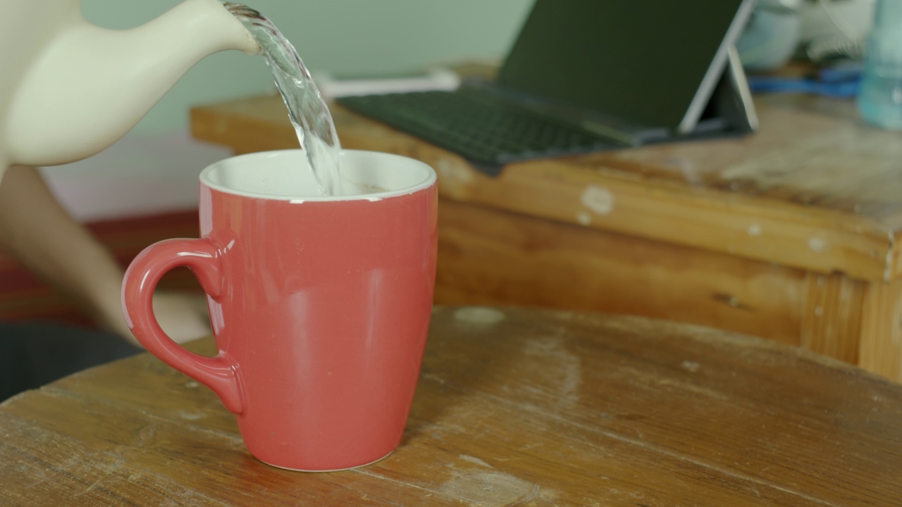 男子把水从水壶倒进红色陶瓷杯视频素材