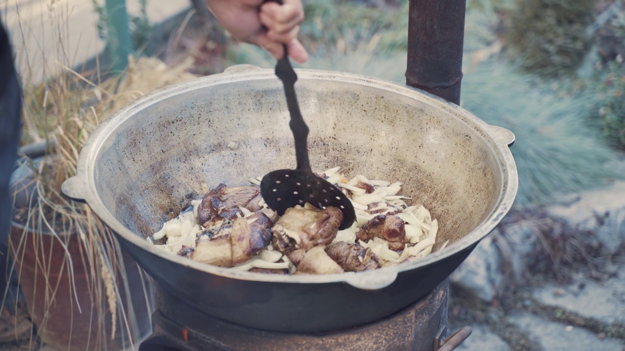 厨师用漏勺在大锅里搅拌肉和蔬菜。视频素材