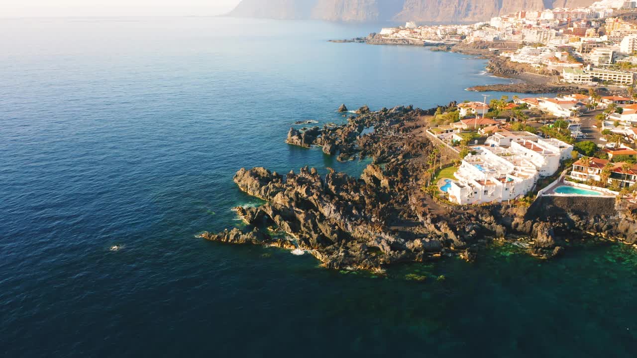 加那利岛火山沿岸的度假住宅。西班牙。蓝色的深海。无人机在特内里费岛老城上空飞行，风景如画。圣地亚哥港一座古老的海滨城市。视频素材