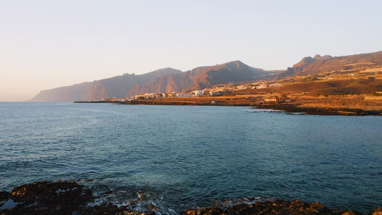 天线。火山岩石海滩。大海波涛平静，海水透明。探索世界。特内里费。西班牙加纳利群岛。美丽的城市风光，度假小镇。旅行上瘾。日落。视频素材