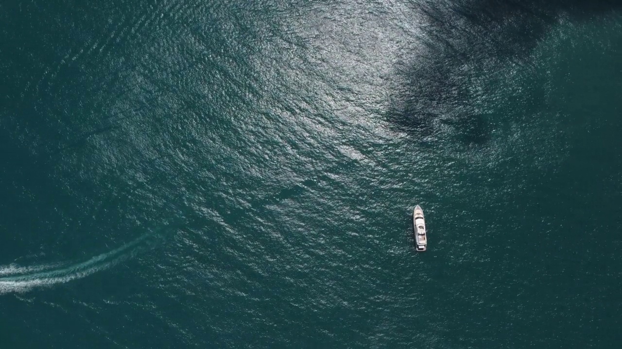 平静海面上的空中游艇。豪华邮轮旅行。从上面看，白色的船在深蓝色的水。航拍的富有的游艇航行在海上。在豪华船上的夏季之旅视频素材