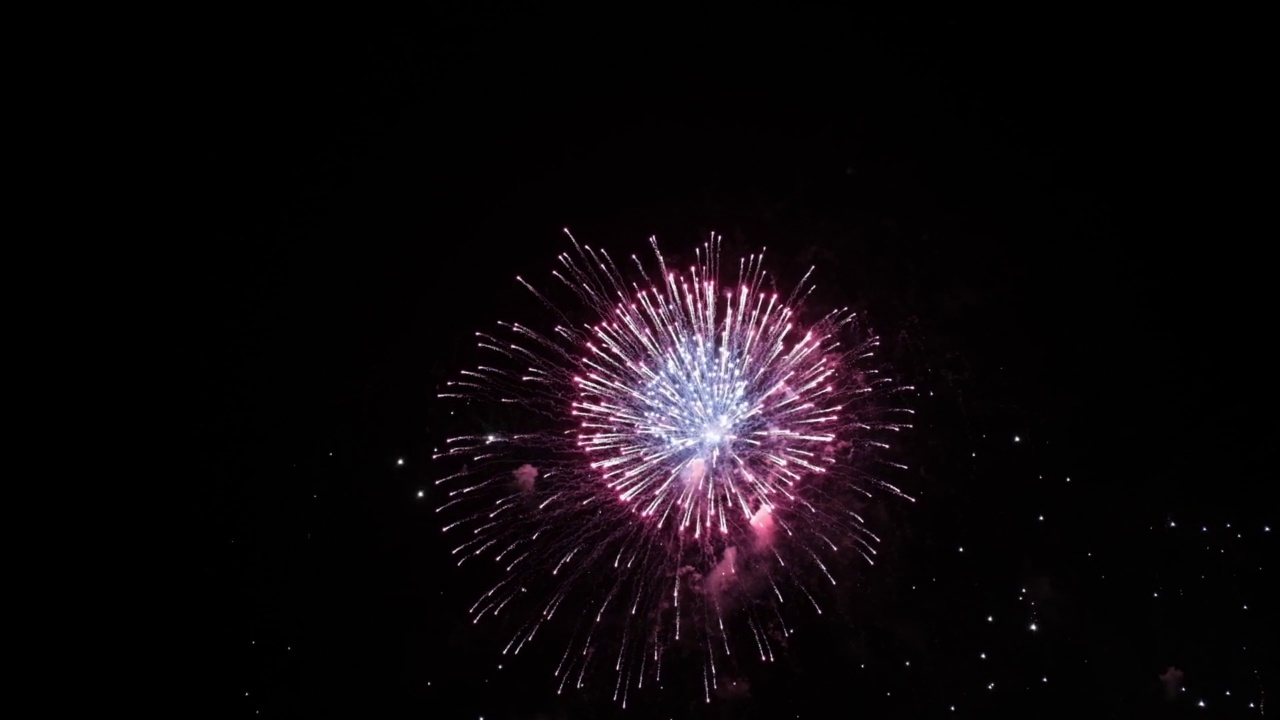 烟花的背景。一个真实的彩色闪耀的烟花与灯光在夜空的抽象图像。闪亮的烟花表演。除夕夜的烟火庆祝活动。视频素材