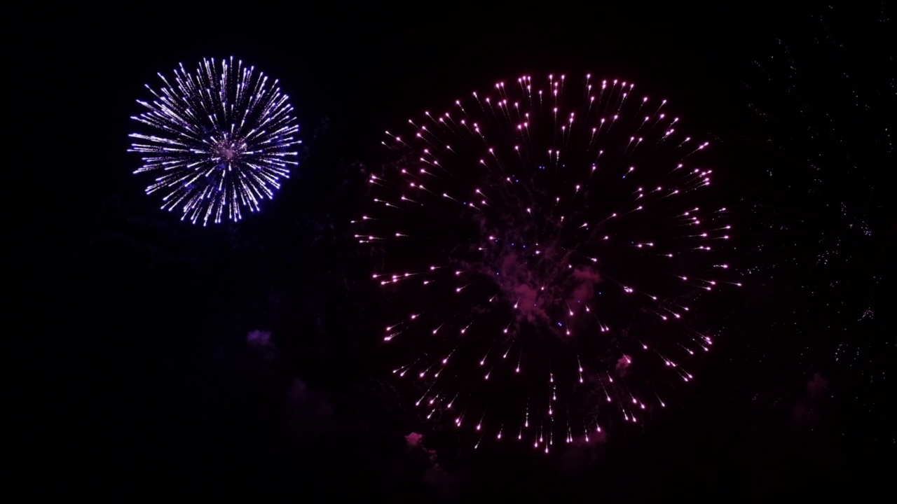 烟花的背景。一个真实的彩色闪耀的烟花与灯光在夜空的抽象图像。闪亮的烟花表演。除夕夜的烟火庆祝活动。视频素材